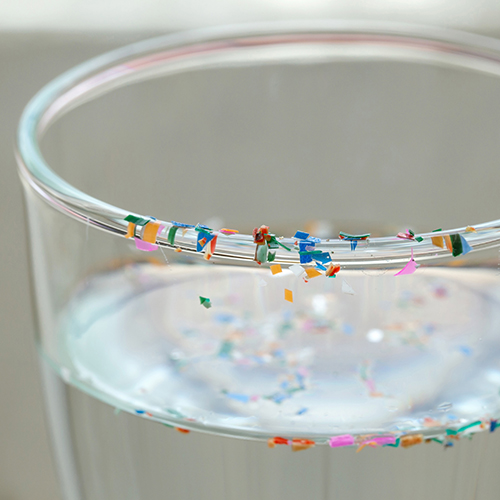 Water glass with plastic particles on the rim